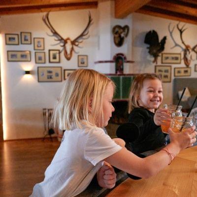 Two children clinking drinks at a rustic bar with wooden decor